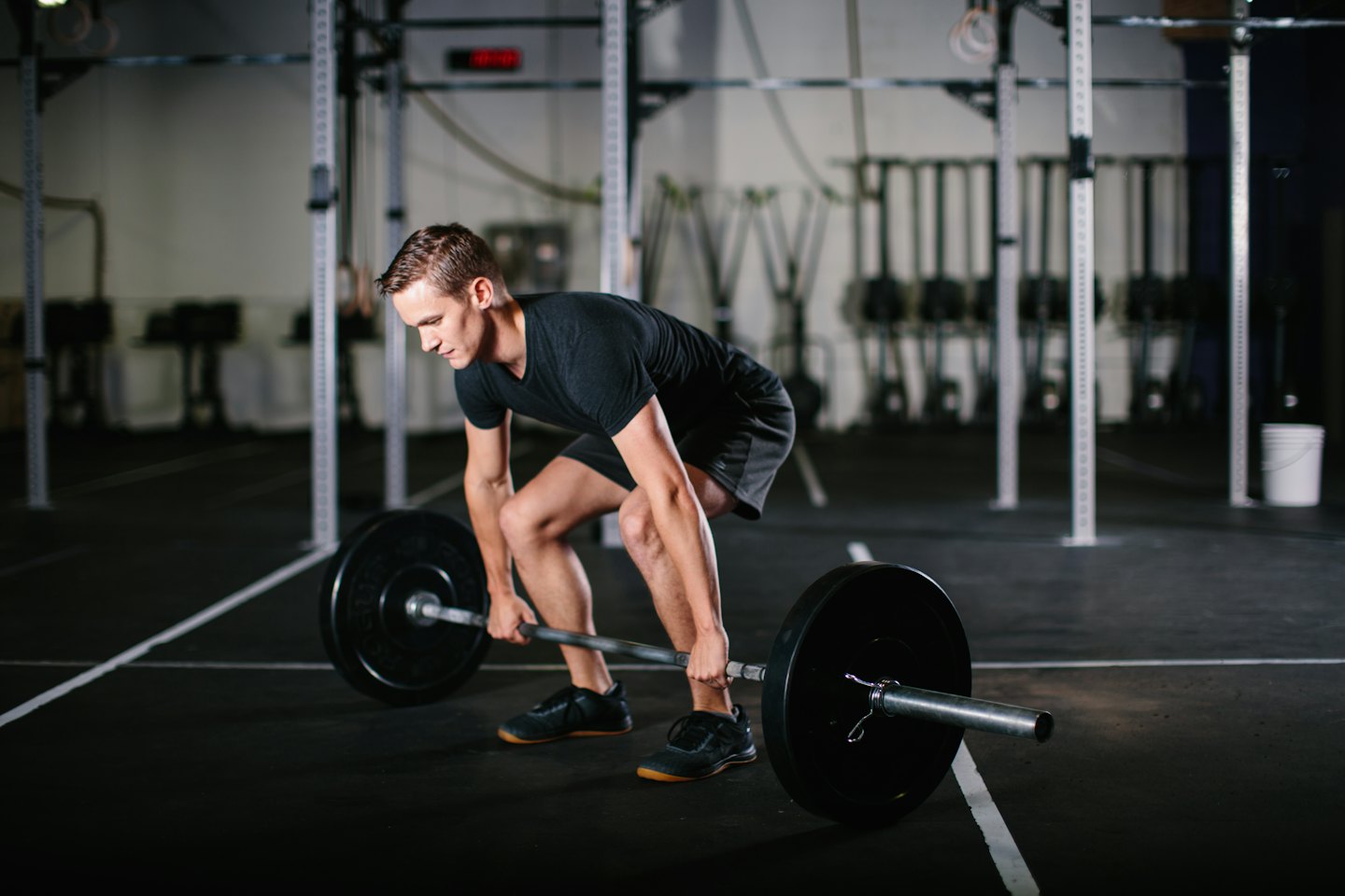 Man in athletic wear deadlifts a barbell in a gym.