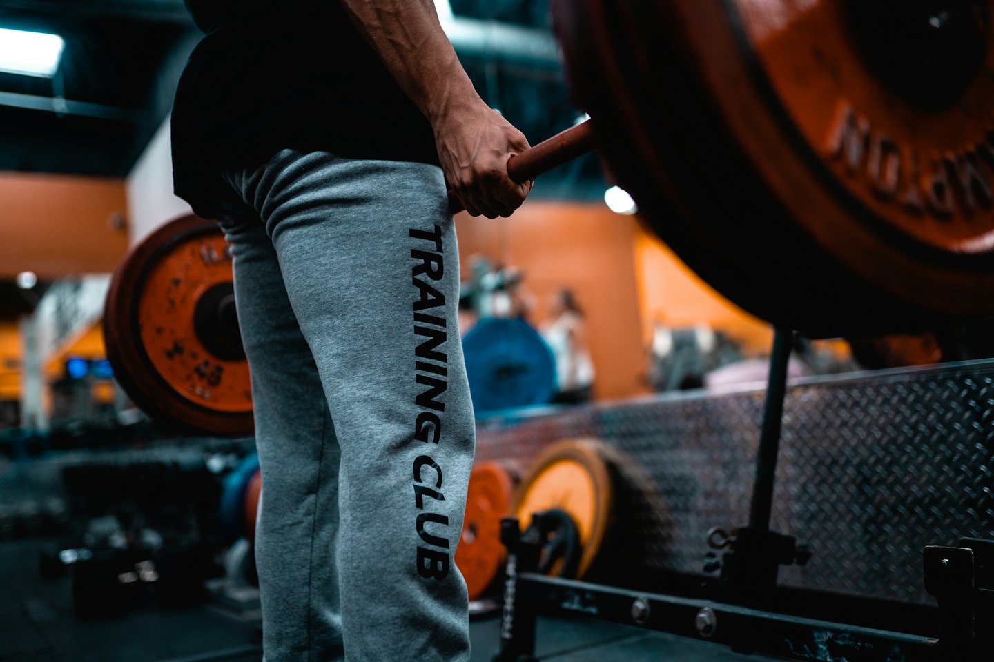Muscular arm lifting a barbell with orange weights.
